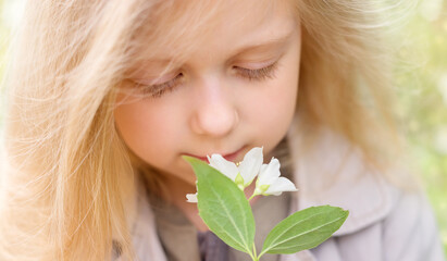 Blonde little girl sniffs Jasmine flowers