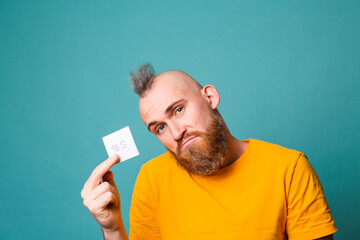 Bearded european man in yellow shirt isolated on turquoise background holding yes with surprise and...