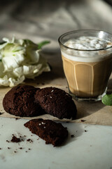 Cappuccino , chocolate cookies and white tulip on marble board on round table.
