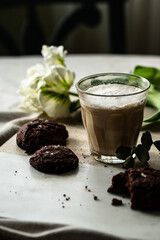 Cappuccino , chocolate cookies and white tulip on marble board on round table.