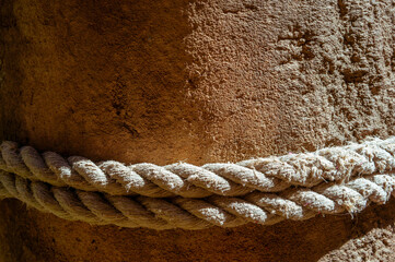 Fototapeta na wymiar Thick rope on large stone pillar