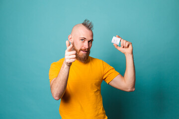 Bearded european man in yellow shirt isolated on turquoise background holding yes with surprise and...