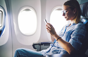 Woman browsing mobile phone in airplane