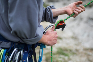Man's hands operating a rock climbing belaying device