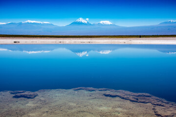 View of volcanoes across a salt lake in the Atacama Desert, Chile.