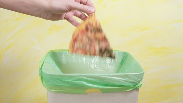 Fast food and unhealthy eating concept hand throwing a pizza in garbage