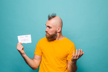 Bearded european man in yellow shirt isolated on turquoise background holding paper with you are...