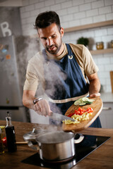 Handsome man preparing pasta in the kitchen. Guy cooking a tasty meal..