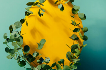 The Easter egg-shaped frame is yellow on a blue green background framed by eucalyptus leaves with hard shadows.