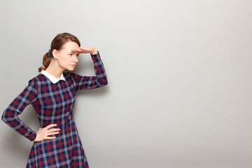 Serious girl is gazing into the distance and trying to look something