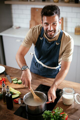 Handsome man preparing pasta in the kitchen. Guy cooking a tasty meal..