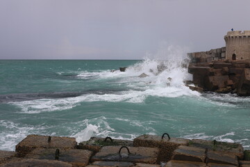 Waves breaking on rocks. Scenic landscape on a cold rainy day. View of big wave crashing on rock....