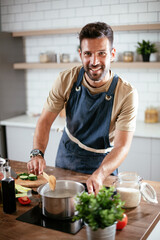 Handsome man preparing pasta in the kitchen. Guy cooking a tasty meal..