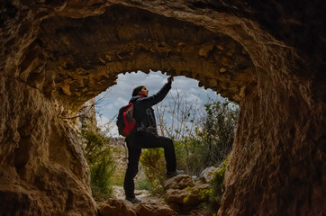 Obraz premium A girl is observing the rocks on the entrance of a cave