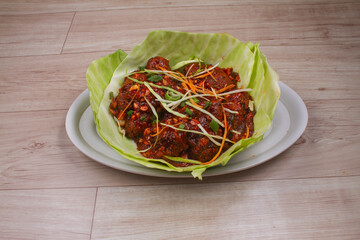 Paneer Chilis is an Indian dish, paneer cubes with tomatoes, onions, spring onions, chilli sauce. served on rustic wooden background, selective focus