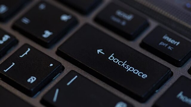 Human fingers press the Backspace key on the computer keyboard.
