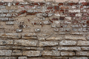 Old grungy rustic dirty dusty brick wall of ancient city. Uneven pitted peeled surface brickwork of cellar worn.Ruined rusty red stiff blocks. Spotted messy ragged holes brickwall for 3D grunge design