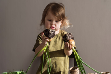 little girl holding green onion with roots in her hands. planting green onion. Zero waste. Clear...