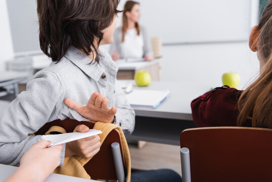 kid giving note to classmate during lesson in school
