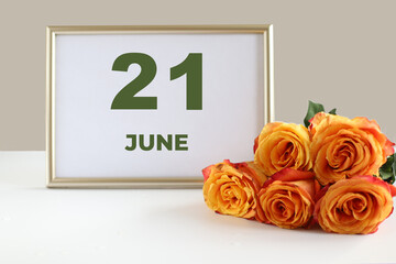 day of the month 21 June calendar photo frame and yellow rose on a white table