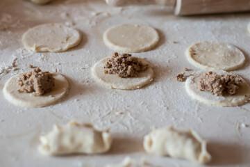 Variki with meat and mushrooms. They lie on the table. Dough.