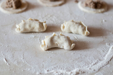 Variki with meat and mushrooms. They lie on the table. Dough.
