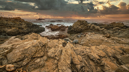 Beautiful seascape, ocean views, rocky coast, sunlight on the horizon. Composition of nature. Sunset scenery background. Cloudy sky. Water Reflection. California Seashore.
