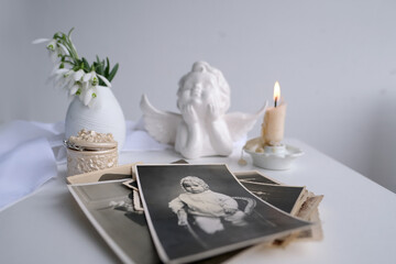 stack of vintage photos, baby photography of 1960, candle is lit, first spring flowers, snowdrop,...