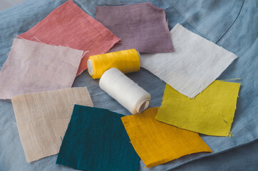 Close up of colour swatches samples of organic linen fabric and sewing thread on aqua green linen textile background. Concept: sustainable, ethical, organic slow fashion 