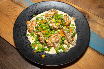 A delicious plate of Creamy Chicken with Spring Vegetables on a wooden kitchen table