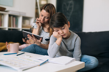 mother helping her son to do homework. he is tired and exhausted