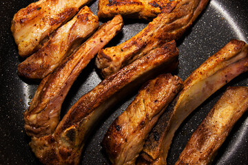 fried pork ribs in a non-stick frying pan.close up