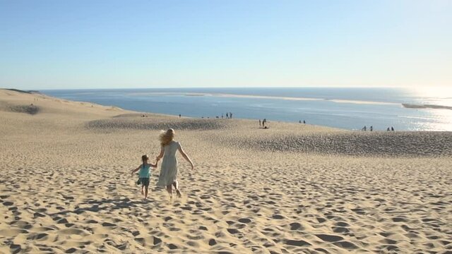 Mother and daughter running on the sand on Dune du Pyla