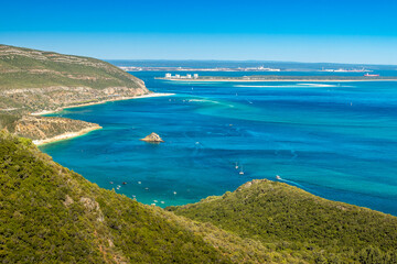 Fototapeta na wymiar Beautiful landscape of the Arrábida Natural Park in Portugal, with the mountains, beaches, blue sea and in the background the Tróia peninsula on a sunny day in summer.