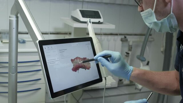 The doctor examines the 3D model of the jaw. A dentist examines a digital image of teeth on a monitor. Modern technologies in medicine and dentistry.