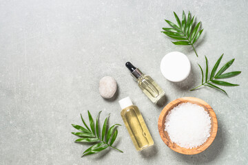 Spa product composition with palm leaves, serum, towel and cosmetic at stone table. Flat lay image with copy space.