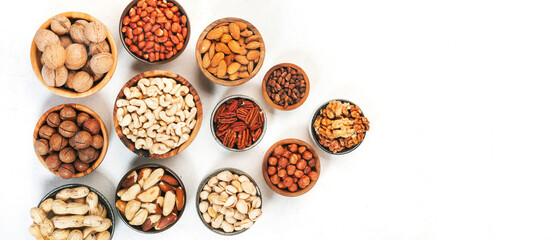 Assortment of nuts in bowls. Cashews, hazelnuts, walnuts, pistachios, pecans, pine nuts, peanuts, macadamia, almonds, brazil nuts. Food mix on white background, top view, copy space