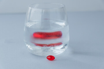 Optical illusion of pill and its reflection in glass water, distortion of objects through water,...