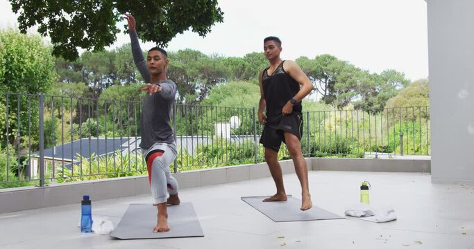 Mixed race gay male couple standing on terrace practicing yoga