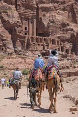 Turistas montados en camellos visitando la antigua ciudad de Petra en Jordania