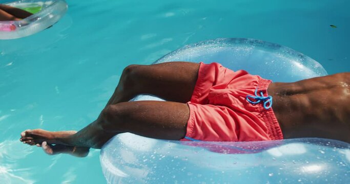 Handsome african american man lying on inflatable sunbathing in swimming pool