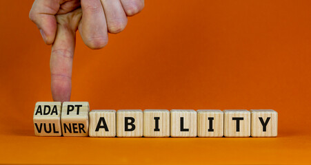 Vulnerability or adaptability symbol. Businessman turns cubes and changes words 'vulnerability' to 'adaptability'. Orange background, copy space. Business, vulnerability or adaptability concept.