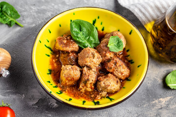 Homemade meatballs with tomato sauce and spices served in yellow plate and a gray background. banner, menu recipe, top view