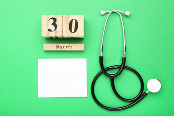 Text Doctor's Day with stethoscope and cube calendar on green background