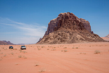 Fototapeta na wymiar Paisaje con vehículos y la montaña de los Siete Pilares en el desierto de Wadi Rum de Jordania