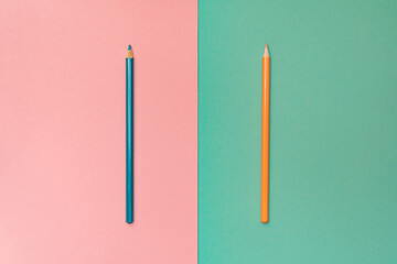 Blue and orange pencils on the pink and turquoise background. Minimalism. Vertical lines