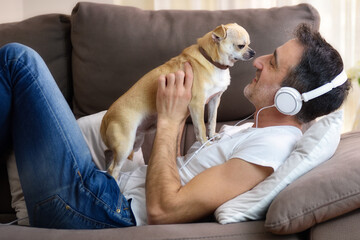Man playing with his dog affectionately lying on sofa detail