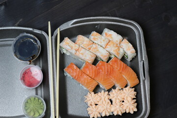 Roll set in box safe delivery with chopstick, sauce on black background