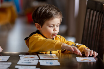 little boy learns words from cards under the ABA therapy program at home at the table - 419438361