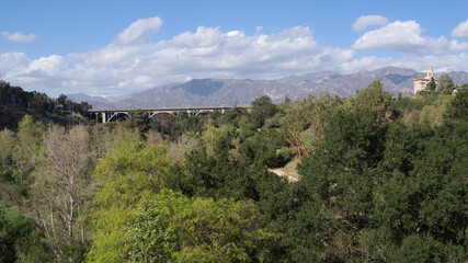 Naklejka premium Panoramic view of the Arroyo Seco, the Colorado Street Bridge, and the Richard Chambers Courthouse against the San Gabriel Mountains in Pasadena.